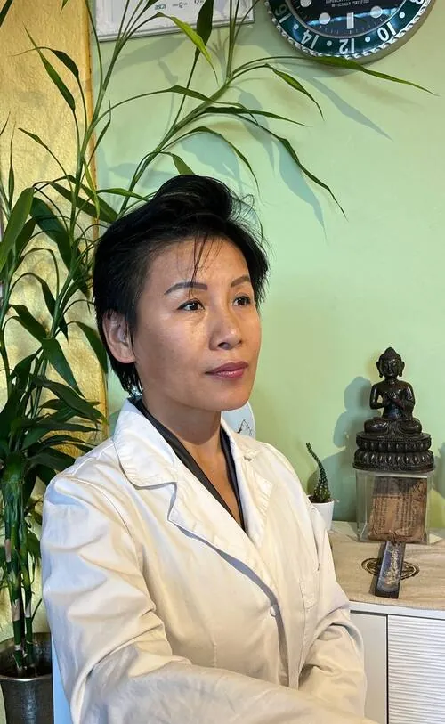 Yana Pan Bossy en blouse blanche dans la salle de soins, une statue de Bouddha à l'arrière-plan
